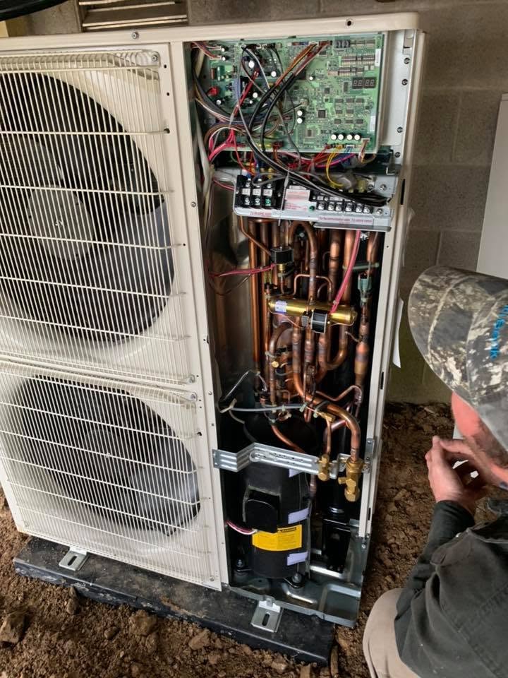 Technician repairing an outdoor heat pump unit